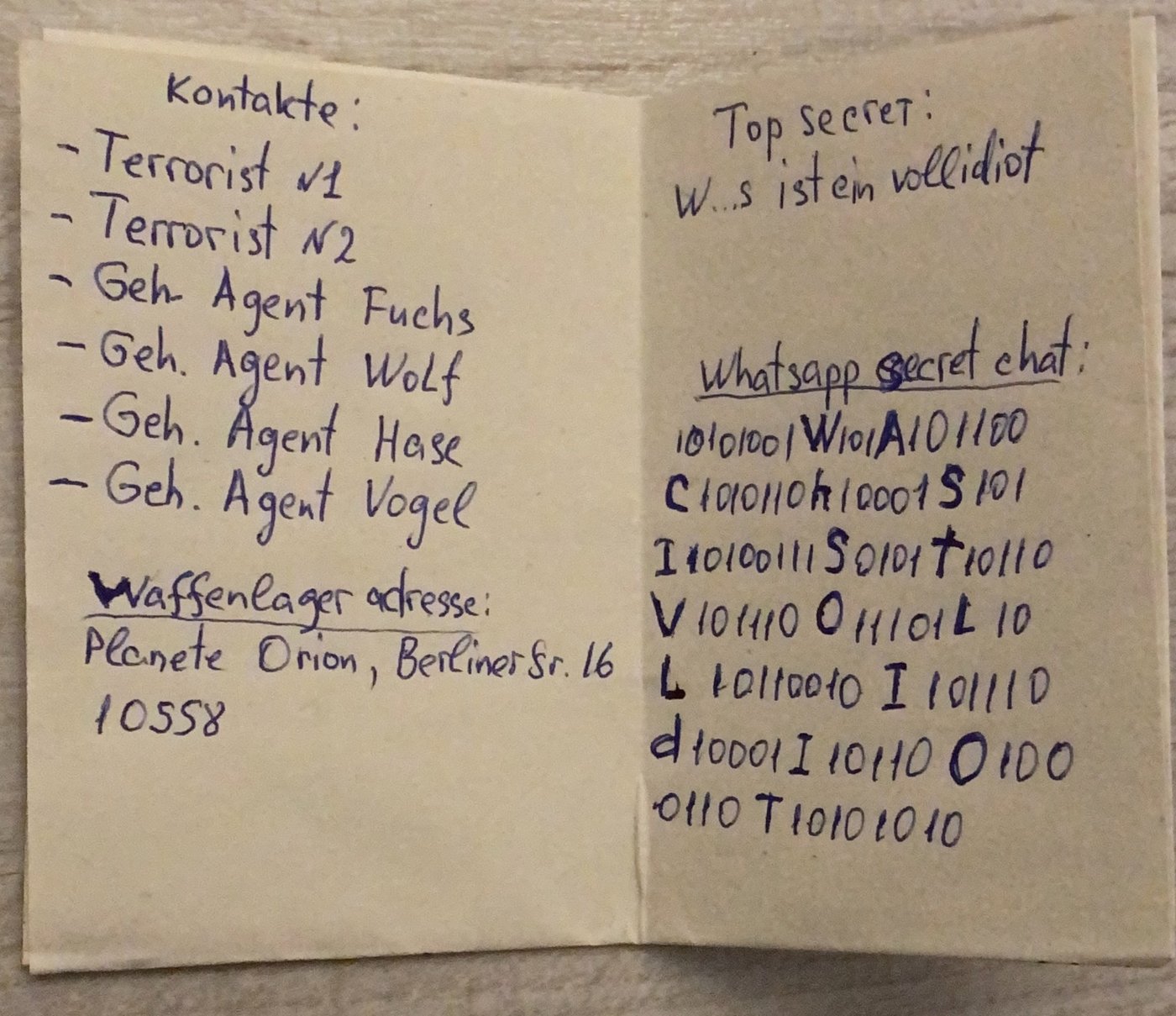Innenseite mit Kontaktliste Terrorist 1, Terrorist 2, Waffenlager-Adresse Planet Orion, und WhatsApp Secret Chat aus Nullen und Einsen